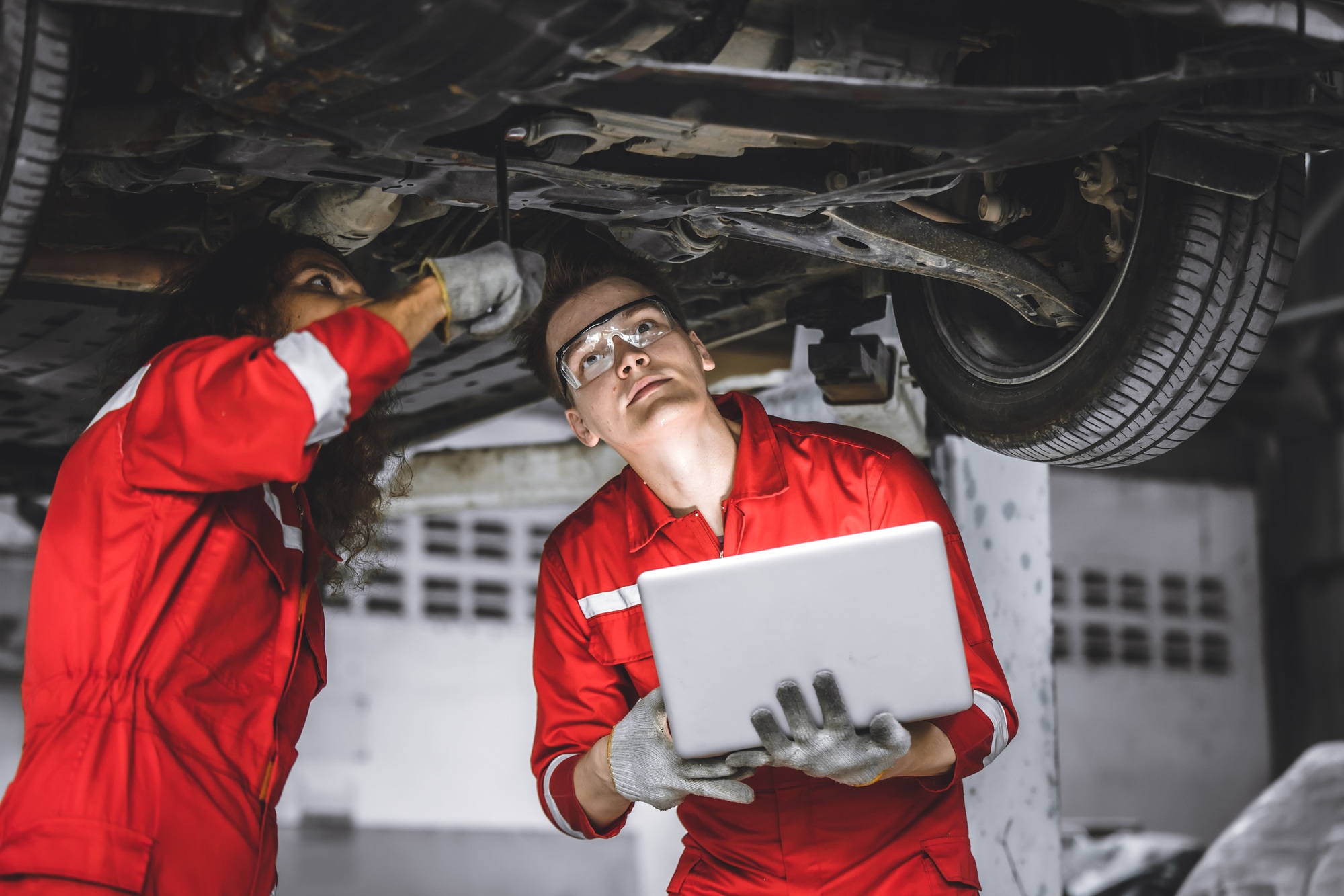 Mechanic male team staff worker working together under car auto service check tuning in garage